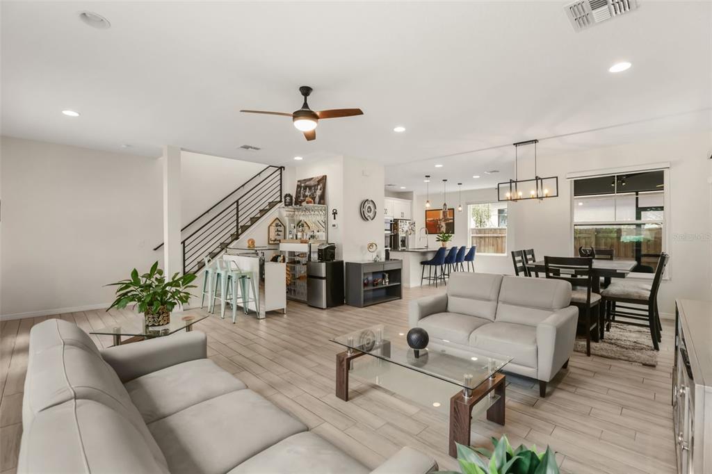 An open-concept living room and kitchen featuring light wood-look tile flooring and a staircase — 2338 S BROWN AVENUE, ORLANDO, FL