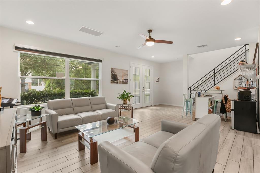 A living room with light tile floors, two grey sofas, a glass coffee table, and stairs — 2338 S BROWN AVENUE, ORLANDO, FL