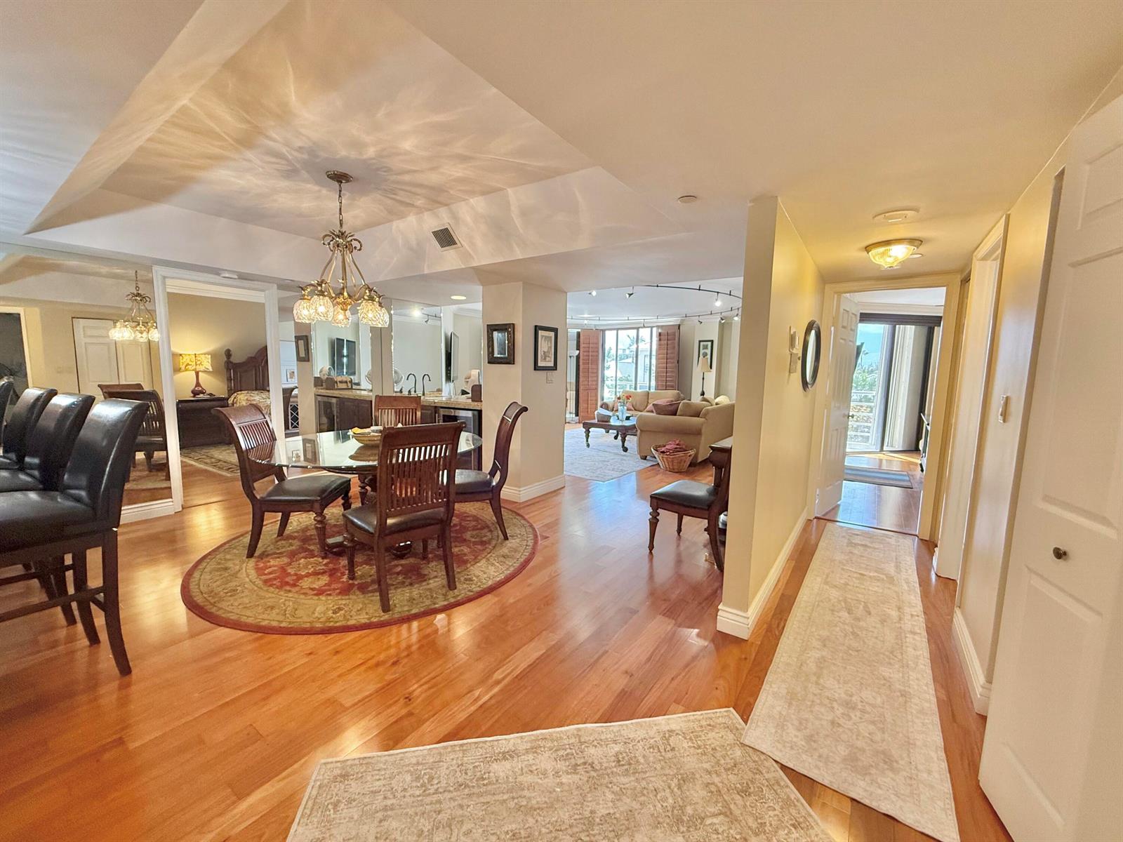 An open-concept dining and living area features hardwood floors, a glass table, and recessed lighting — 176 Helios Drive # 203, Jupiter FL 33477, JUPITER, FL