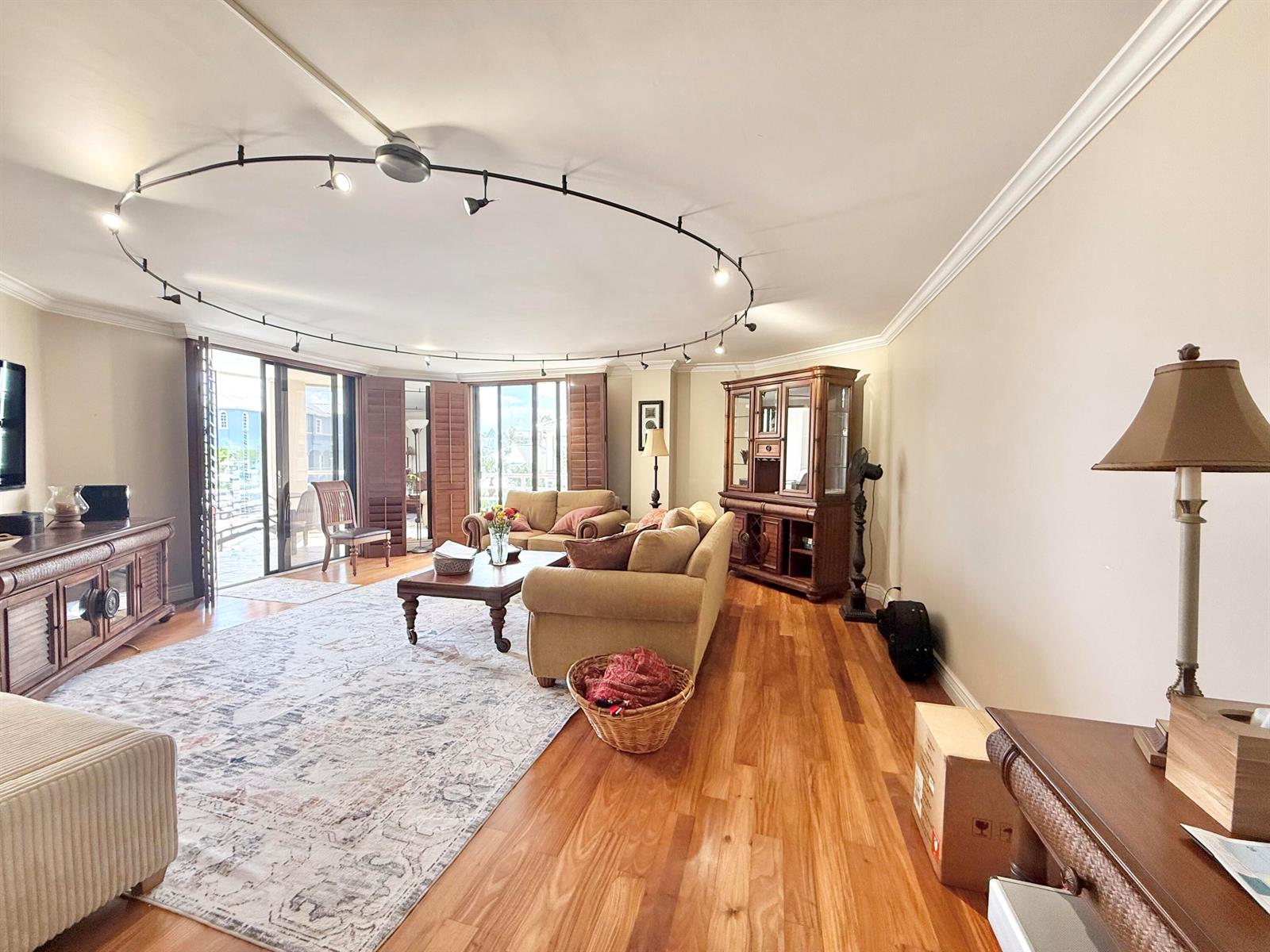 A living room features hardwood floors, a circular track lighting system, and a large rug — 176 Helios Drive # 203, Jupiter FL 33477, JUPITER, FL