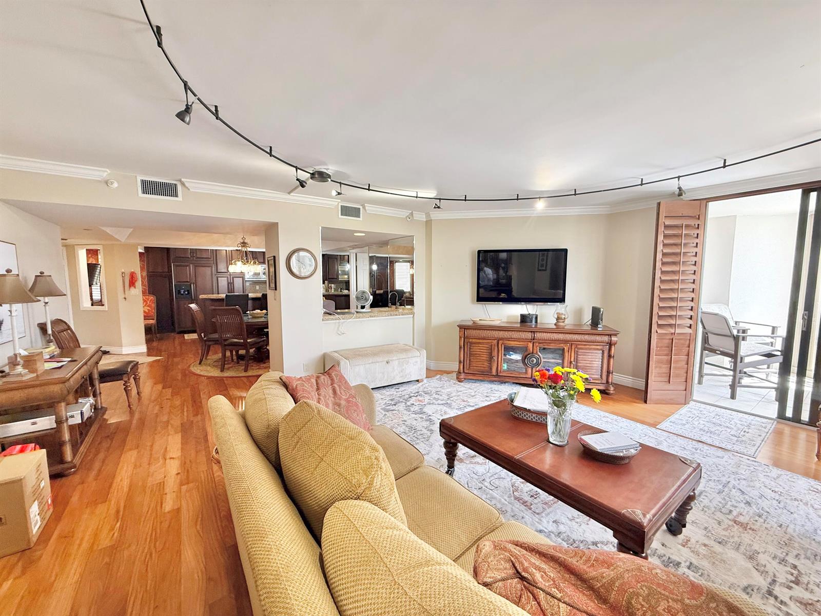 A living room with hardwood floors, a tan sofa, track lighting, and an adjacent dining area — 176 Helios Drive # 203, Jupiter FL 33477, JUPITER, FL