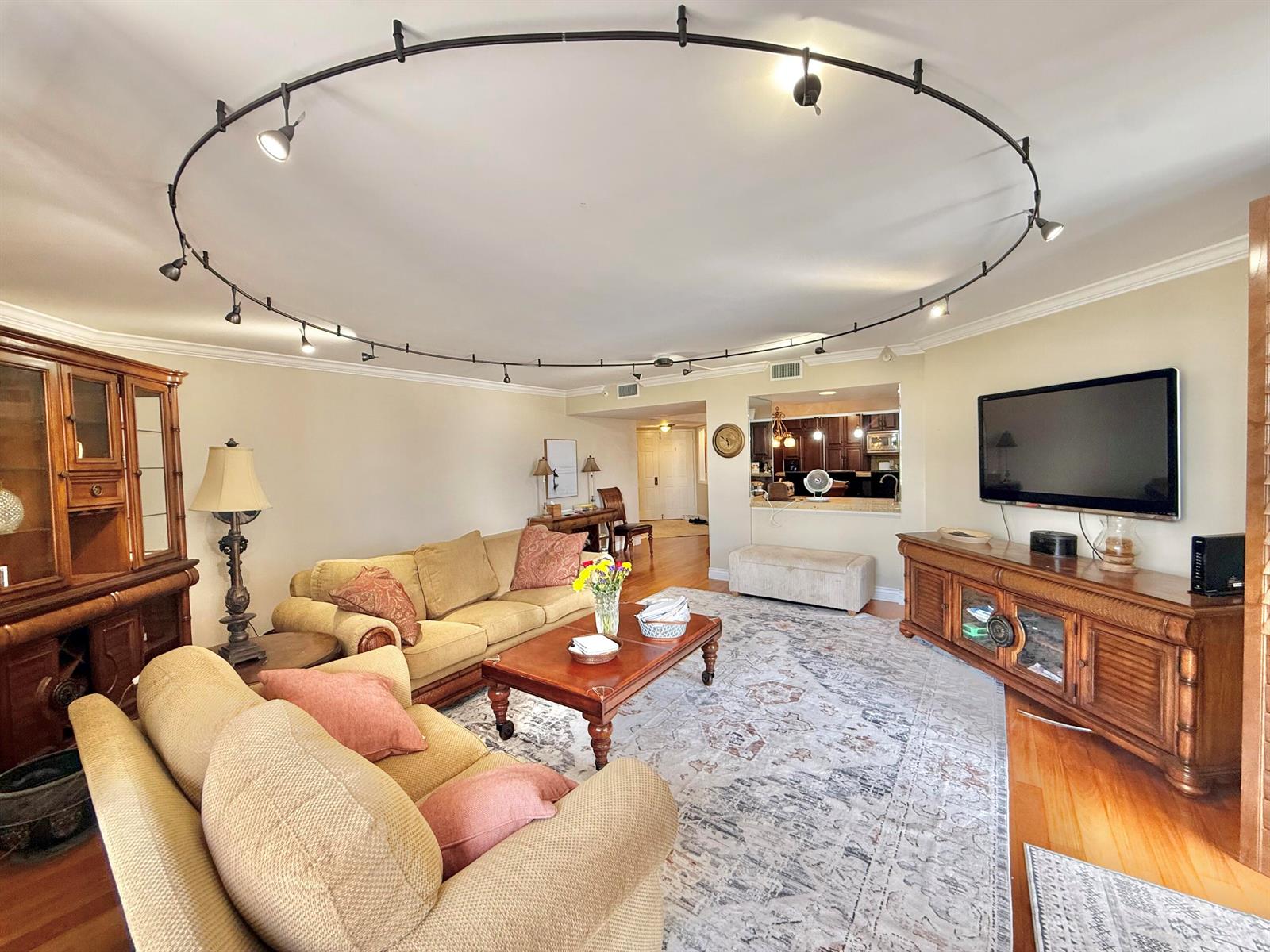 A living room features a circular track lighting system, beige furniture, and a wooden media console — 176 Helios Drive # 203, Jupiter FL 33477, JUPITER, FL