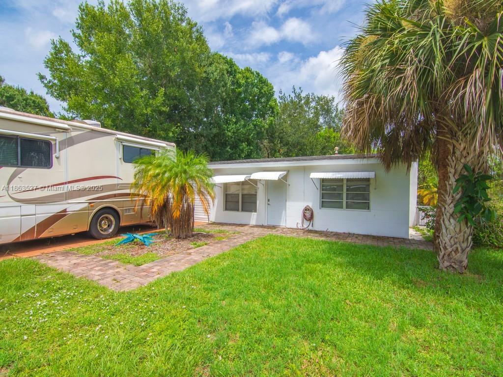 A white house exterior sits next to a large recreational vehicle on a grassy lot — 1650 5 Ave, Vero Beach FL 32960, VERO BEACH, FL