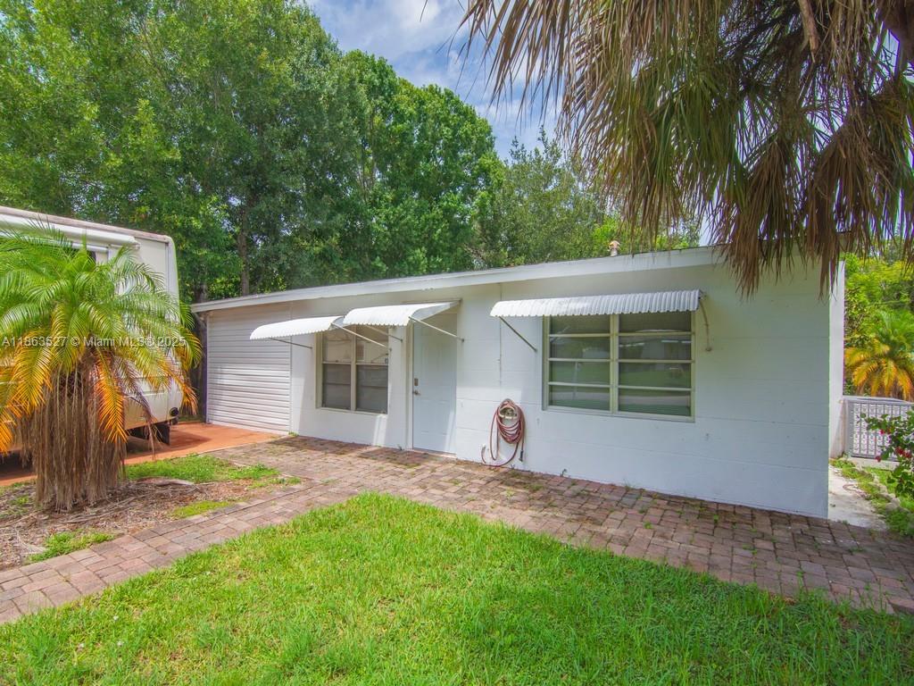 A white, single-story concrete block house features metal window awnings and a brick patio — 1650 5 Ave, Vero Beach FL 32960, VERO BEACH, FL