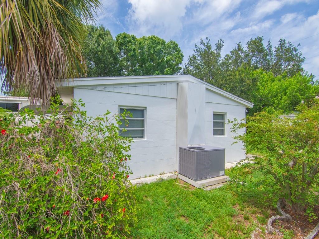 The exterior of a white, single-story house features a central air conditioning unit and windows — 1650 5 Ave, Vero Beach FL 32960, VERO BEACH, FL
