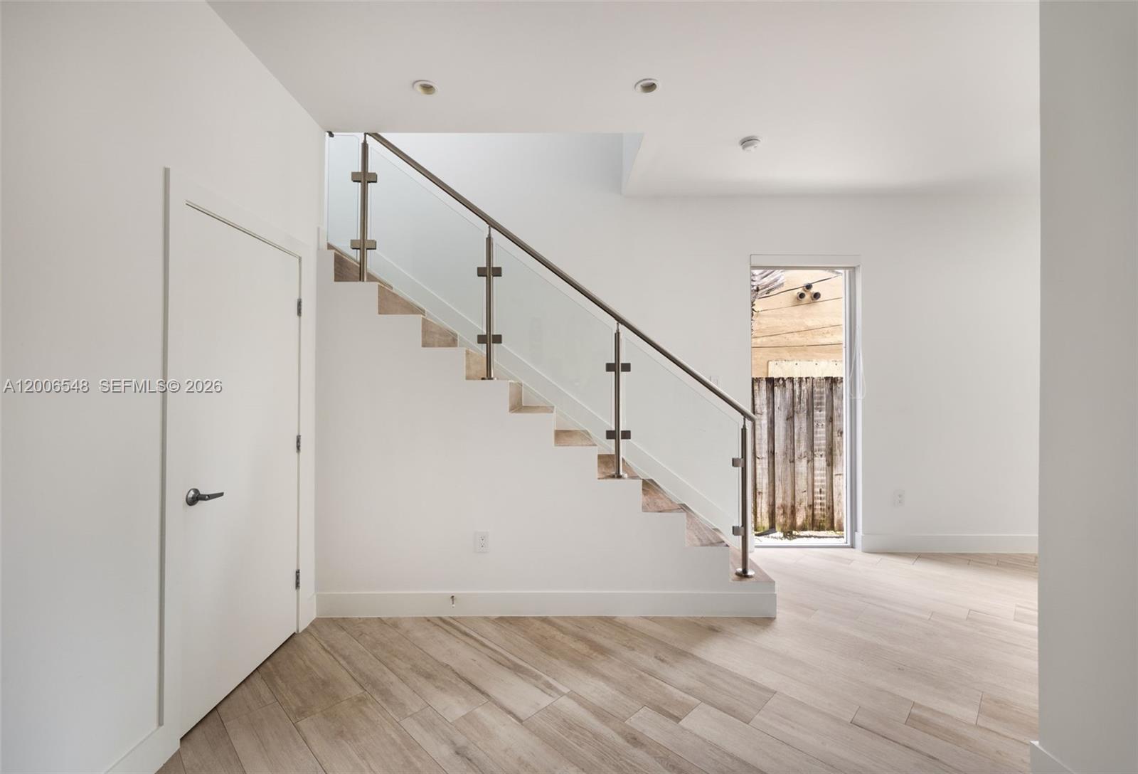 A modern interior features white walls, light wood-look flooring, and a glass-railed staircase — 2931 SW 27th Ter # 2931, Miami FL 33133, MIAMI, FL