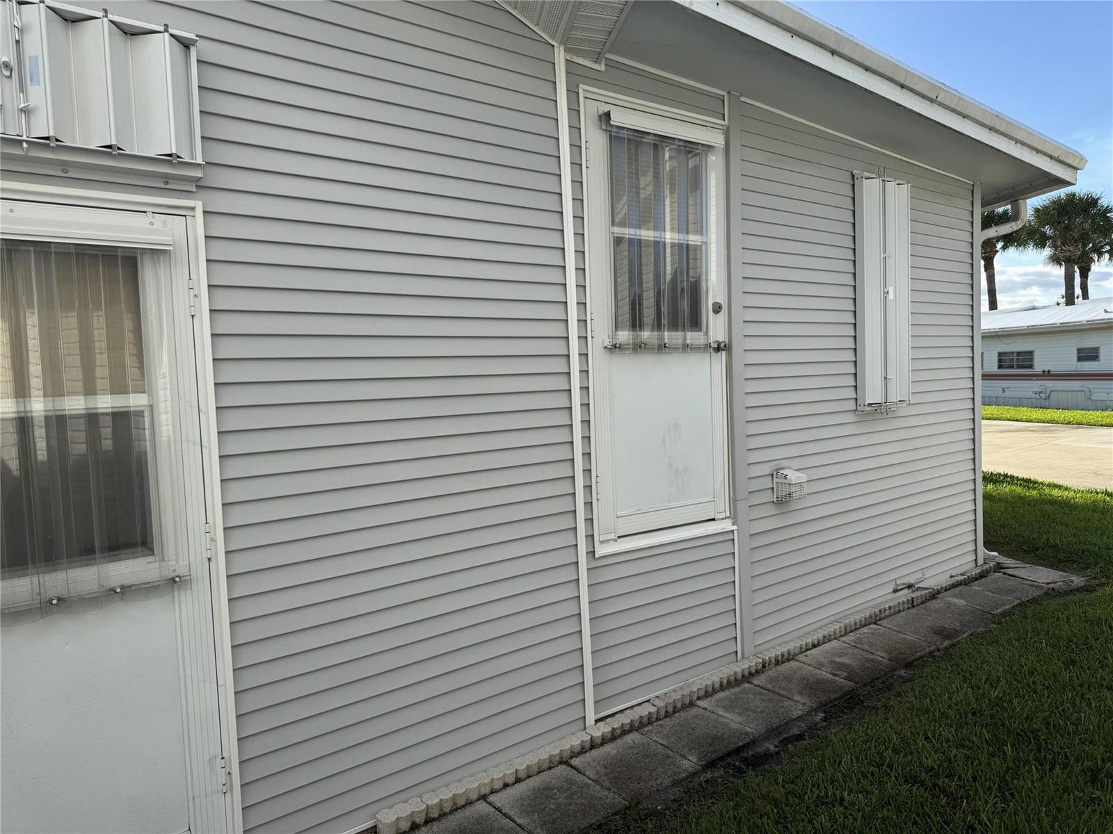 The exterior of a house features gray horizontal siding, two white doors, and storm shutters — 6475 52nd Street, Okeechobee FL 34974, OKEECHOBEE, FL