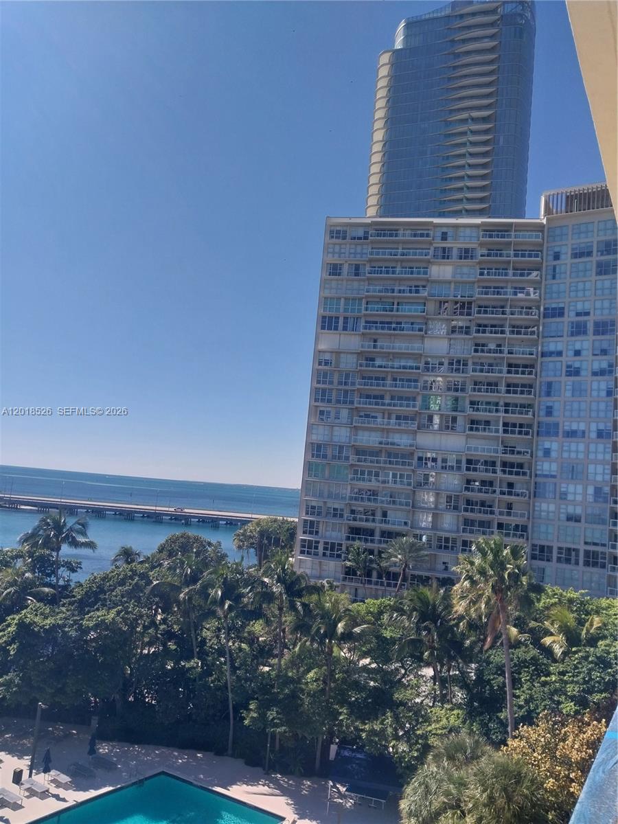 A view from a balcony overlooks a swimming pool, palm trees, a bridge, and buildings — 2333 Brickell Ave # 602, Miami FL 33129, MIAMI, FL