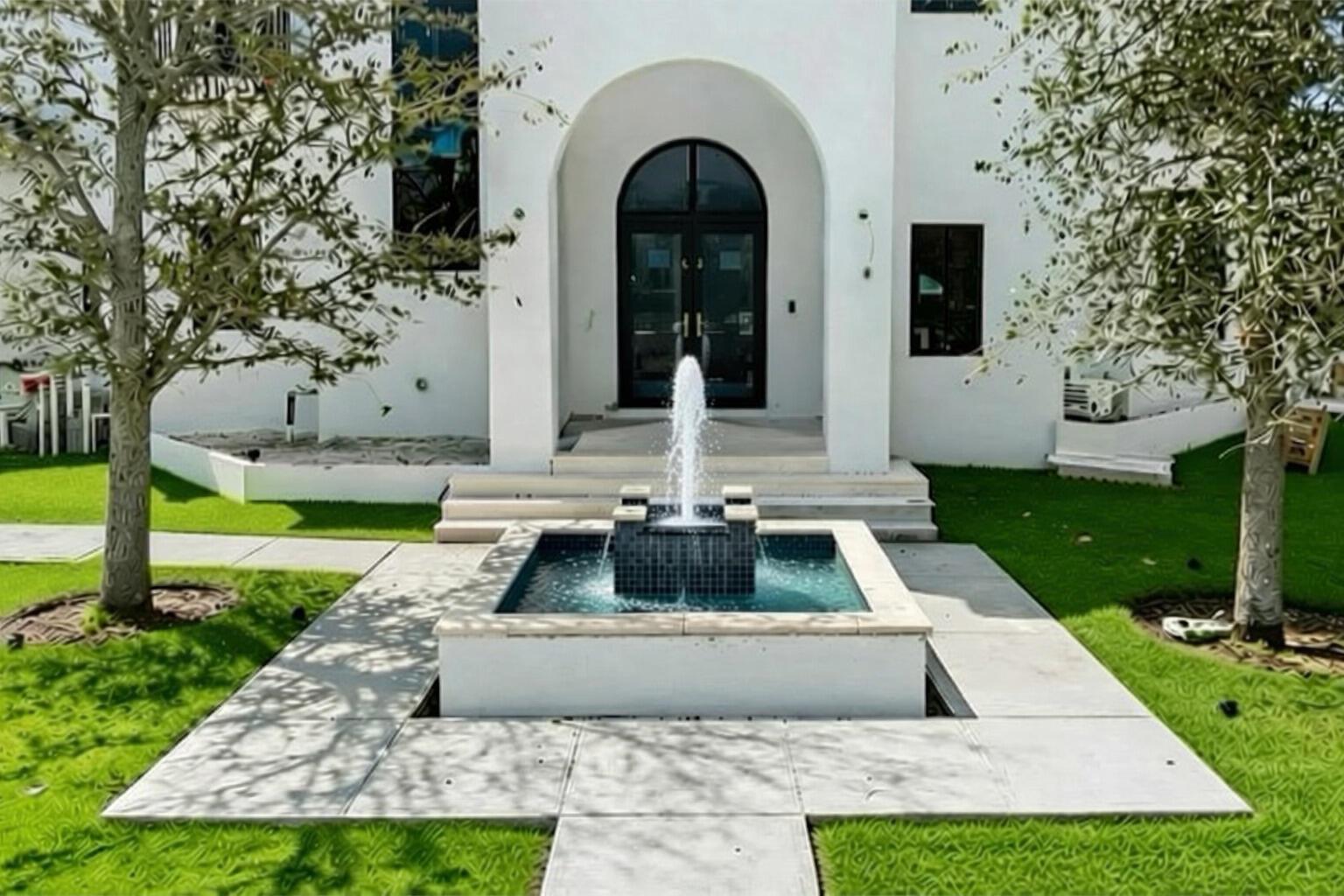 A white house exterior features an arched entryway, a central fountain, and two olive trees — 298 NE 8th Street, Boca Raton FL 33432, BOCA RATON, FL