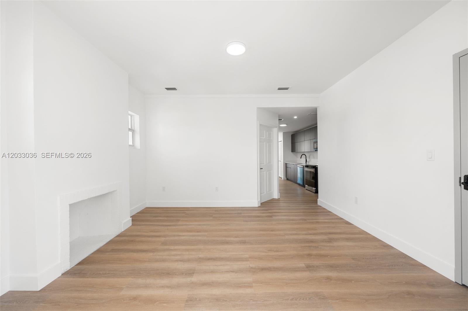 A bright, empty room features white walls, wood-look flooring, and a fireplace opening — 403 SW 12th Ave # 3, Miami FL 33130, MIAMI, FL