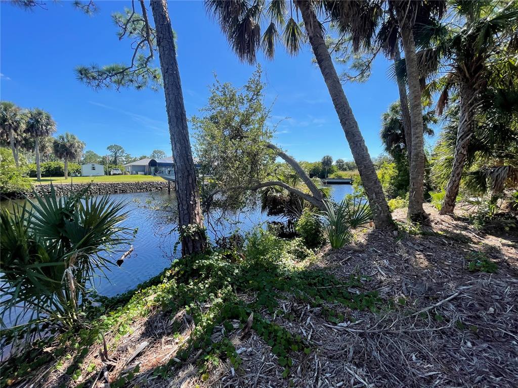 A view of a canal bordered by trees and vegetation with a house in the distance — 1221 UNDERHILL CIRCLE, PORT CHARLOTTE, FL