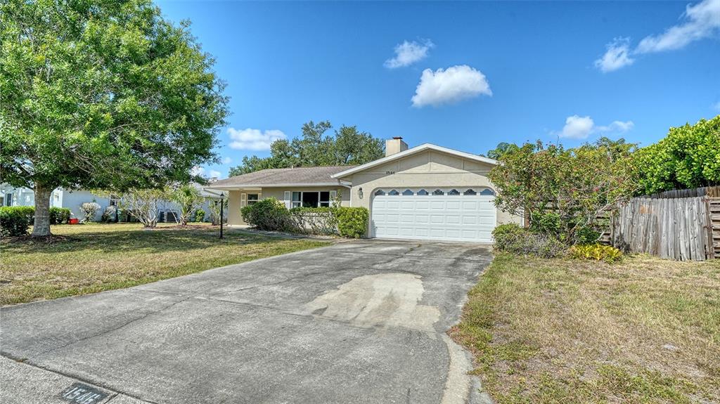 A single-story house with a white garage door and a concrete driveway under a blue sky — 1546 GEORGETOWNE LANE, SARASOTA, FL