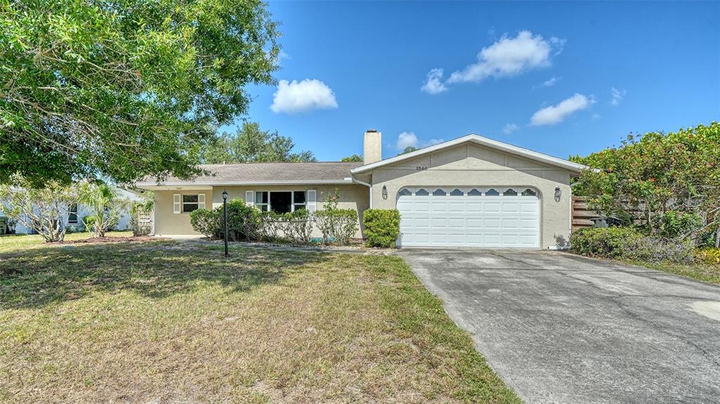 A single-story house with a beige exterior, a two-car garage, and a large front lawn — 1546 GEORGETOWNE LANE, SARASOTA, FL