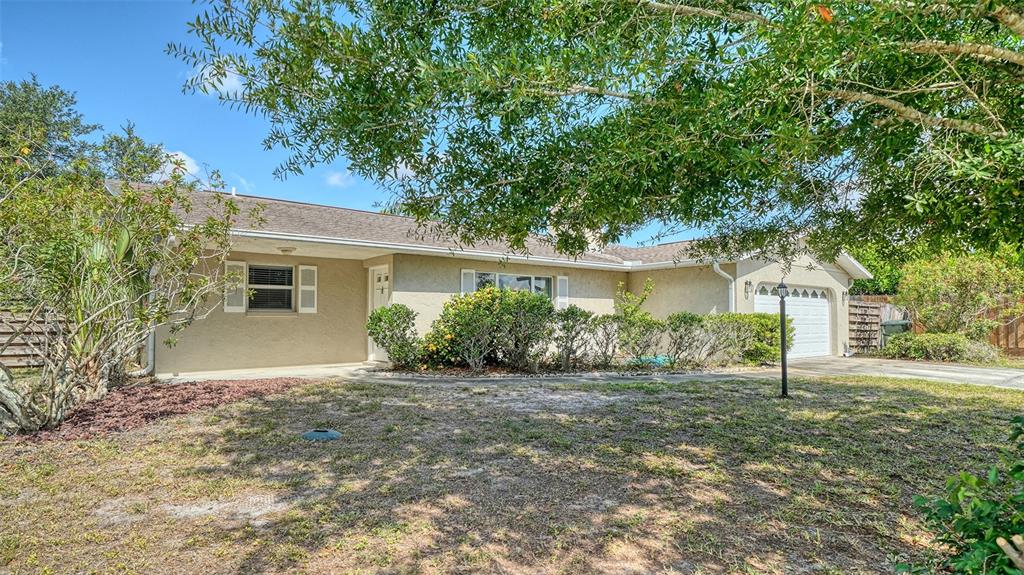 A single-story house with a beige stucco exterior, a garage, and a large front yard — 1546 GEORGETOWNE LANE, SARASOTA, FL