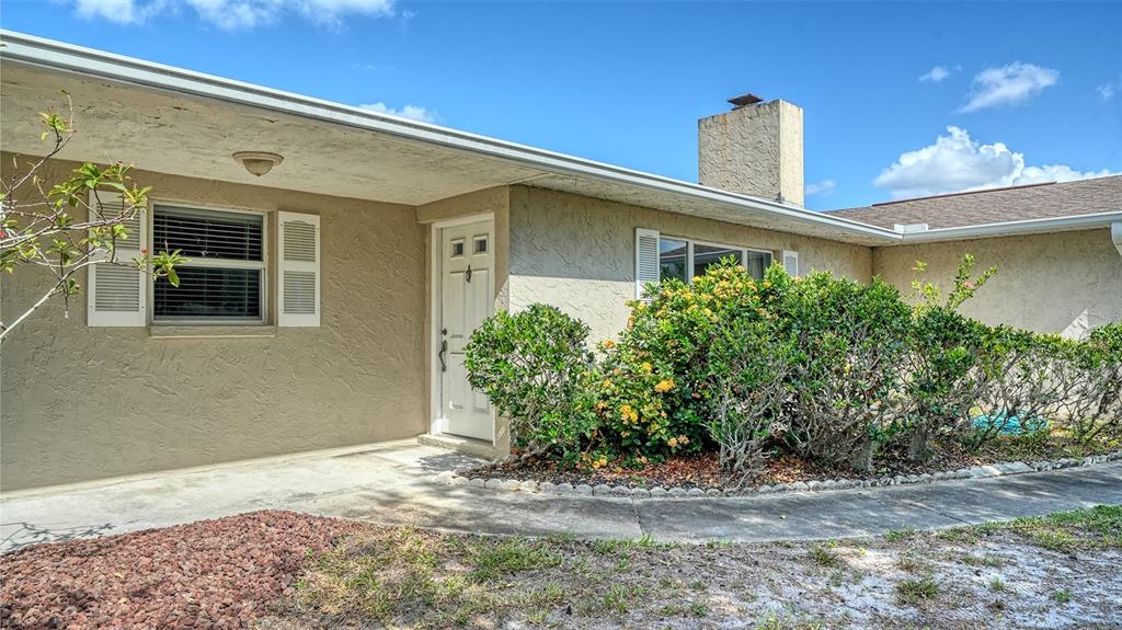 The exterior of a single-story house features a stucco facade, a chimney, and a walkway — 1546 GEORGETOWNE LANE, SARASOTA, FL