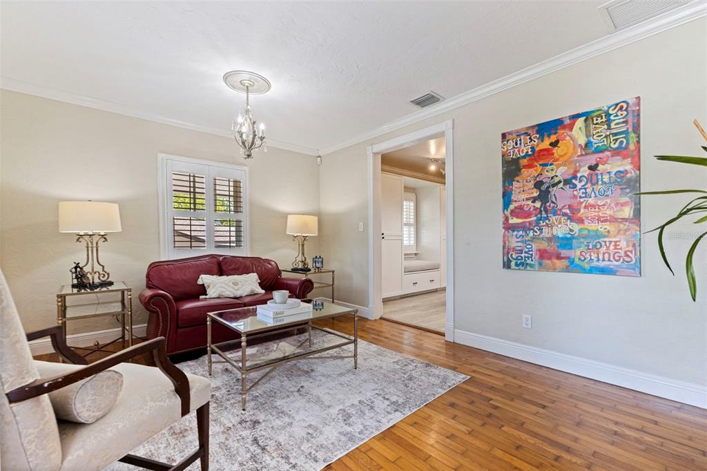 A living room features a red leather sofa, glass coffee table, and colorful wall art — 1010 43RD AVENUE N, ST PETERSBURG, FL
