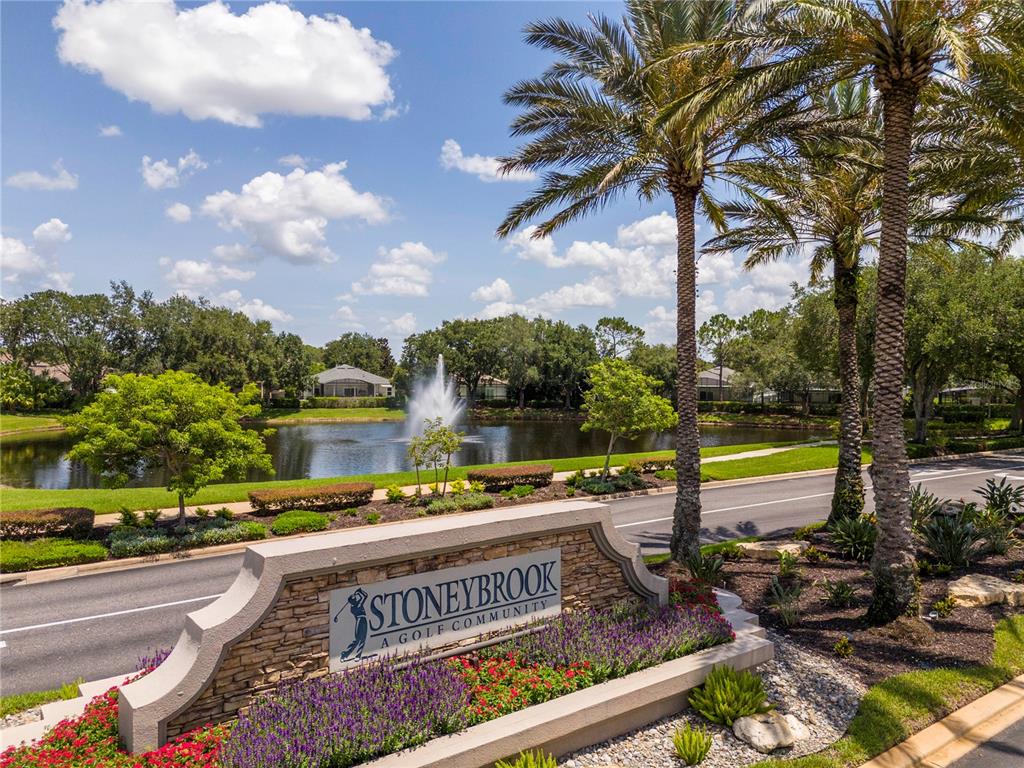 A stone entrance sign for Stoneybrook golf community sits beside a pond with a fountain — 14938 HARTFORD RUN DRIVE, ORLANDO, FL
