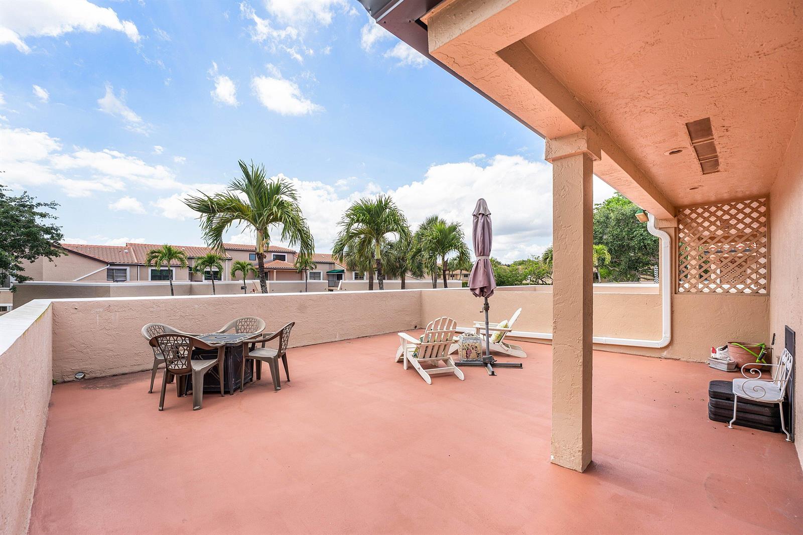 A spacious outdoor rooftop terrace features a dining set, lounge chairs, and palm tree views — 6614 Villa Sonrisa Drive # 123, Boca Raton FL 33433, BOCA RATON, FL