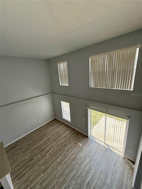 A high-ceilinged living room features light gray walls, wood-look flooring, and large vertical windows — 5445 CHANDLER DRIVE, WINTER HAVEN, FL