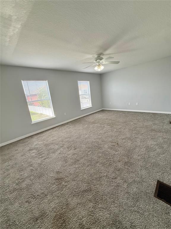 An empty room features gray walls, gray carpeting, two windows, and a ceiling fan — 5445 CHANDLER DRIVE, WINTER HAVEN, FL