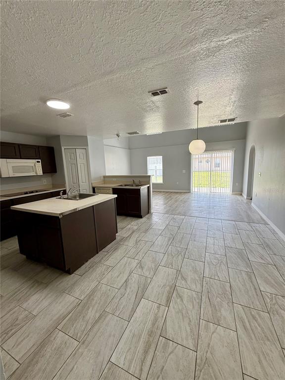 A kitchen with a center island, dark cabinets, and light tile flooring opens to a living area — 5445 CHANDLER DRIVE, WINTER HAVEN, FL
