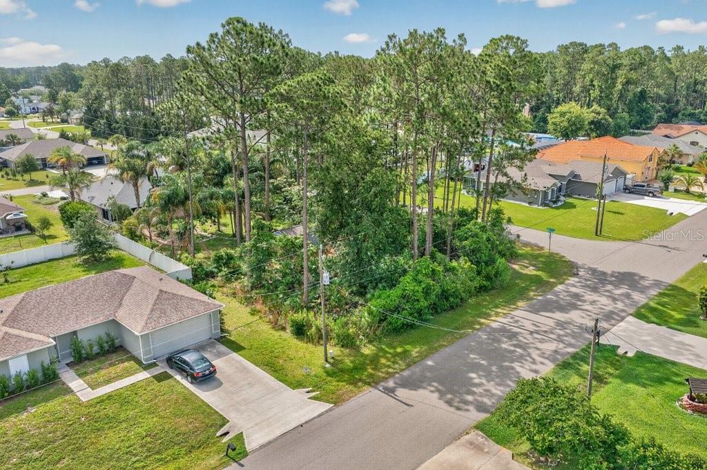 An aerial view shows a vacant, wooded residential lot situated between two suburban houses — 0 RYAN DR, PALM COAST, FL