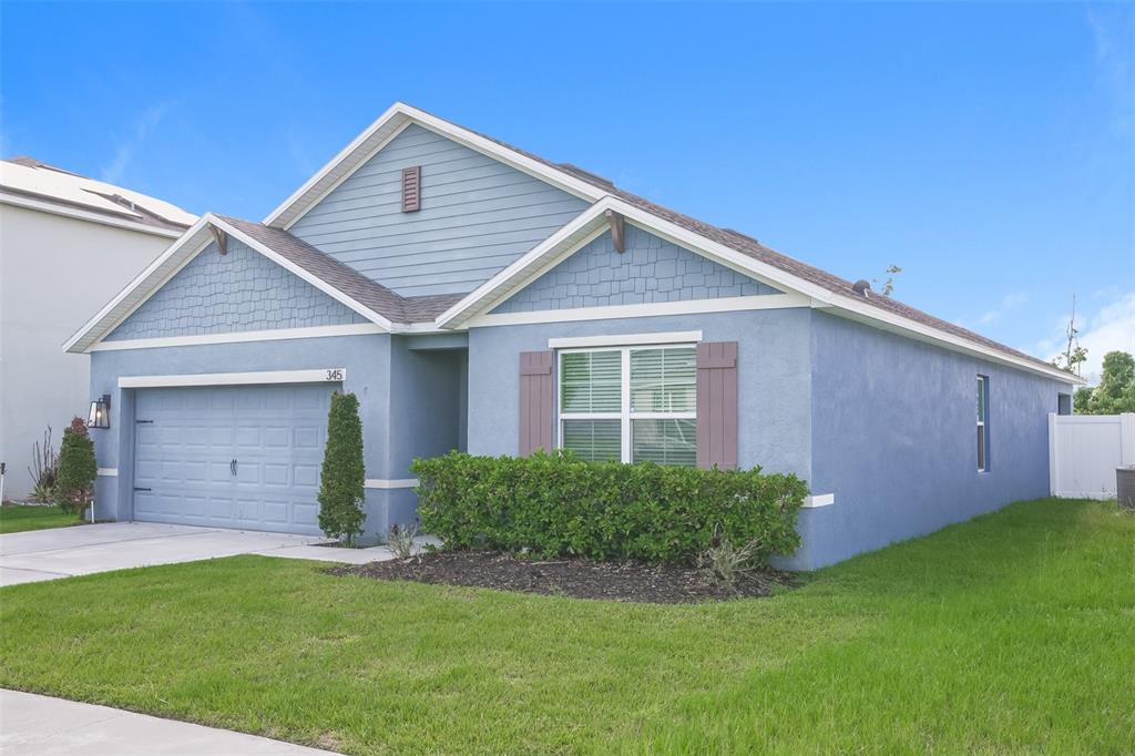 A blue single-story house features a two-car garage, shingle siding, and a front lawn — 345 SUMMERSHORE DRIVE, AUBURNDALE, FL
