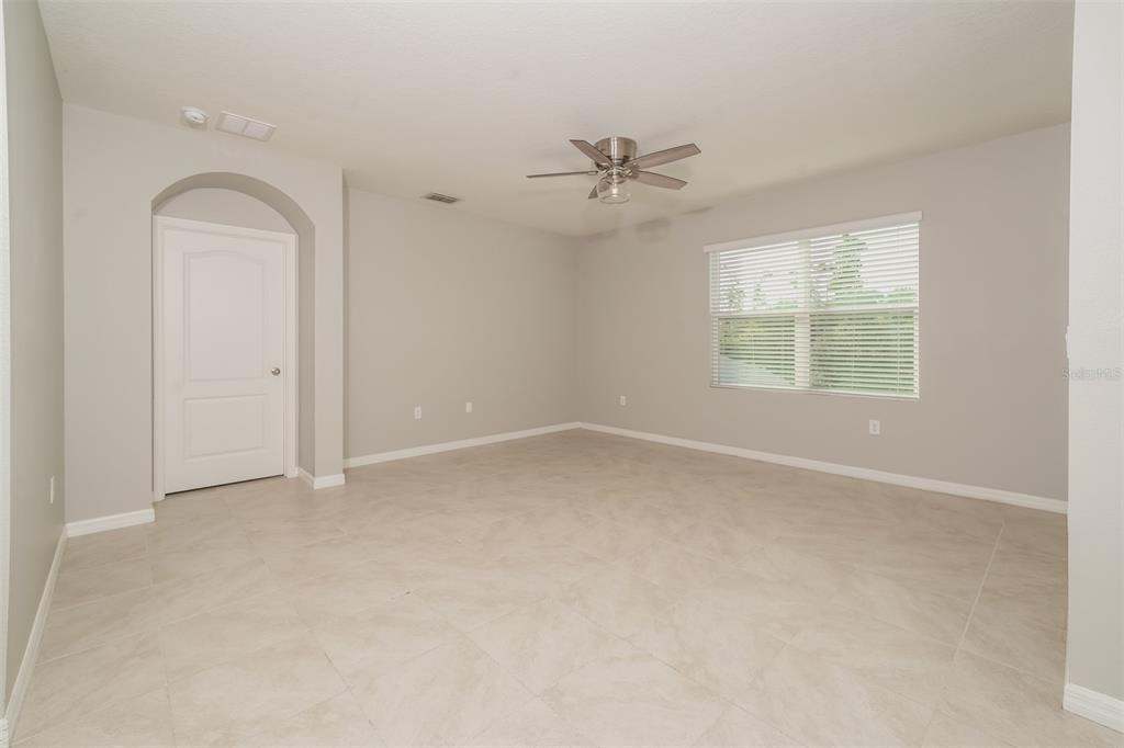 A spacious room with light gray walls, tile flooring, a ceiling fan, and a window — 345 SUMMERSHORE DRIVE, AUBURNDALE, FL