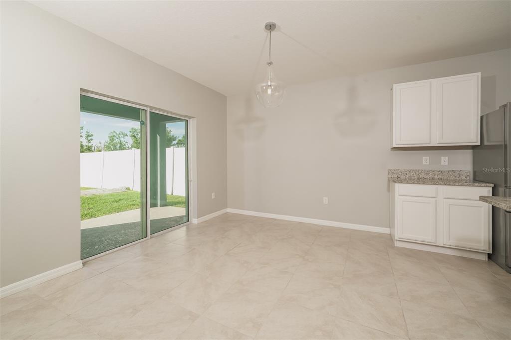 A dining area features tile flooring, white cabinets, granite countertops, and a sliding glass door — 345 SUMMERSHORE DRIVE, AUBURNDALE, FL