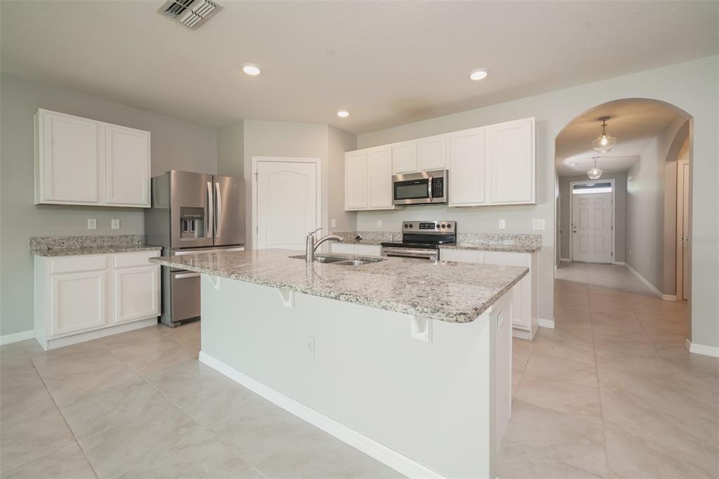 A kitchen features white cabinets, granite countertops, a center island, and stainless steel appliances — 345 SUMMERSHORE DRIVE, AUBURNDALE, FL