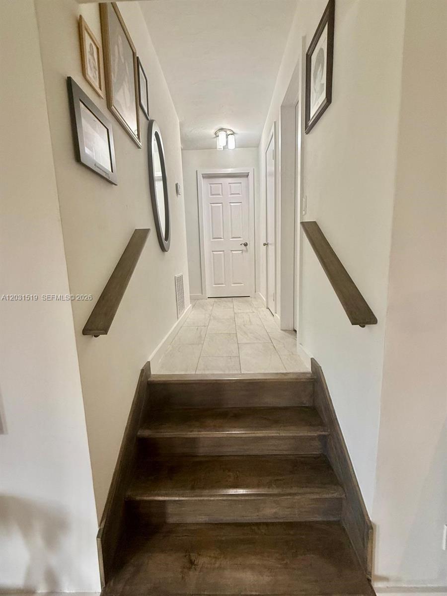A staircase leads up to a narrow hallway with tiled flooring and framed wall art — 17800 NW 14th Pl, Miami Gardens FL 33169, MIAMI GARDENS, FL