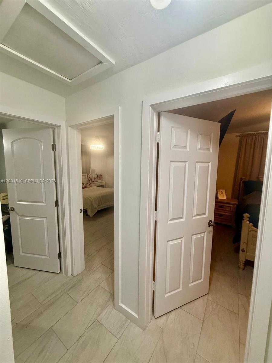 A hallway with light-colored tile flooring leads to two open bedroom doorways — 17800 NW 14th Pl, Miami Gardens FL 33169, MIAMI GARDENS, FL