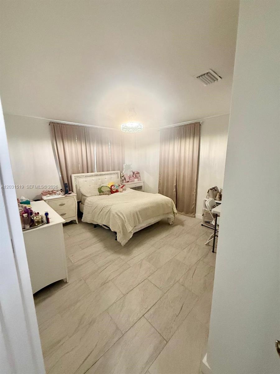 A bedroom features light-colored tile flooring, a bed with a white headboard, and beige curtains — 17800 NW 14th Pl, Miami Gardens FL 33169, MIAMI GARDENS, FL