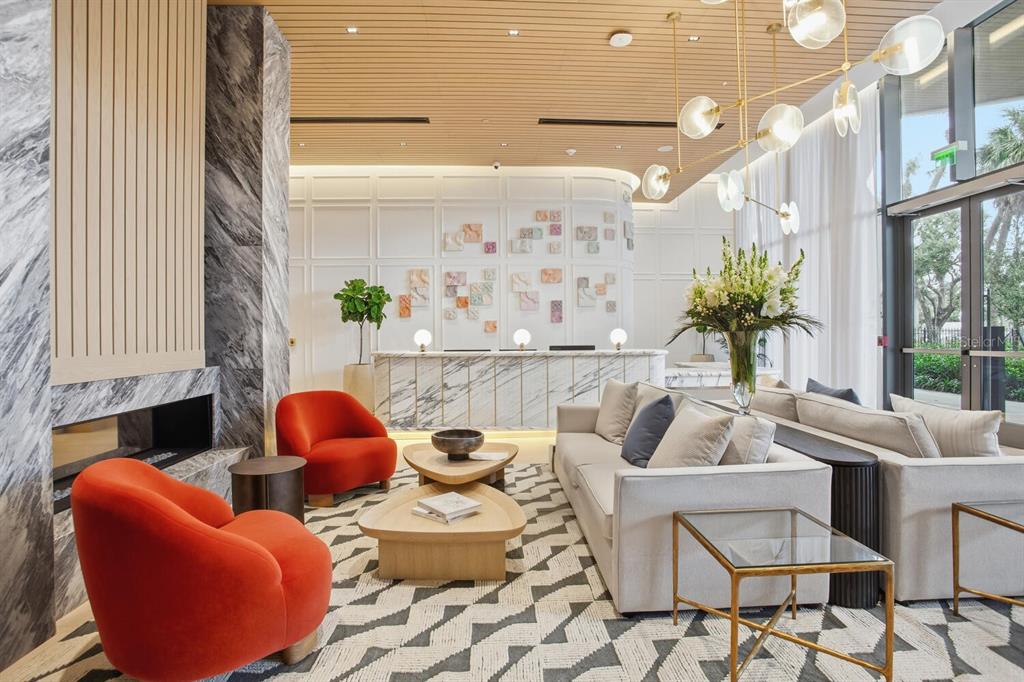 A modern lobby features a marble reception desk, orange armchairs, and a geometric patterned rug — 3015 S YSABELLA AVENUE UNIT 2303, TAMPA, FL