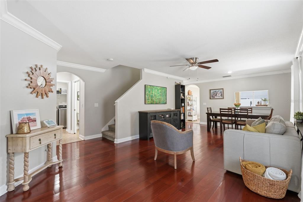 A living and dining area with hardwood floors, a staircase, and neutral-colored walls — 7323 LUMBER PORT DRIVE, RUSKIN, FL