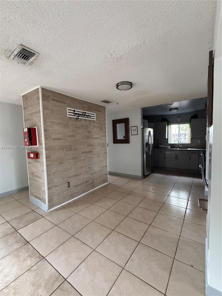 A living room features tiled floors, a gray sofa, and a textured accent wall — 17902 NW 81st Ct, Hialeah FL 33015, HIALEAH, FL