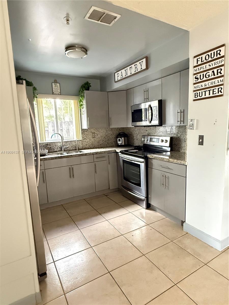 A tiled dining area features a stone-accented wall and an open doorway to the kitchen — 17902 NW 81st Ct, Hialeah FL 33015, HIALEAH, FL