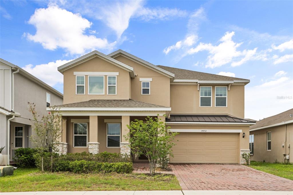 A two-story suburban house with a tan stucco exterior, a front porch, and a garage — 14452 CRESTAVISTA AVENUE, CLERMONT, FL
