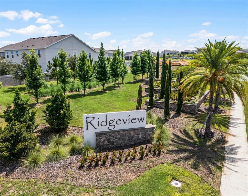 An exterior view of a community entrance sign labeled Ridgeview with landscaping and nearby houses — 14452 CRESTAVISTA AVENUE, CLERMONT, FL