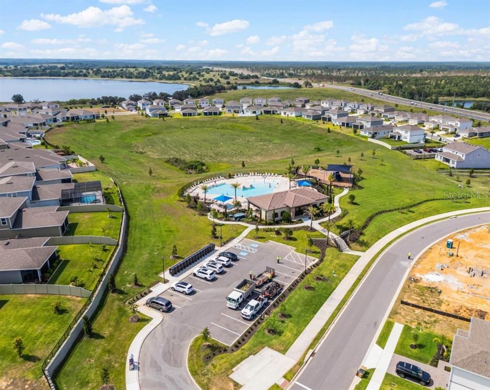 An aerial view shows a suburban neighborhood with a central community pool and clubhouse — 14452 CRESTAVISTA AVENUE, CLERMONT, FL