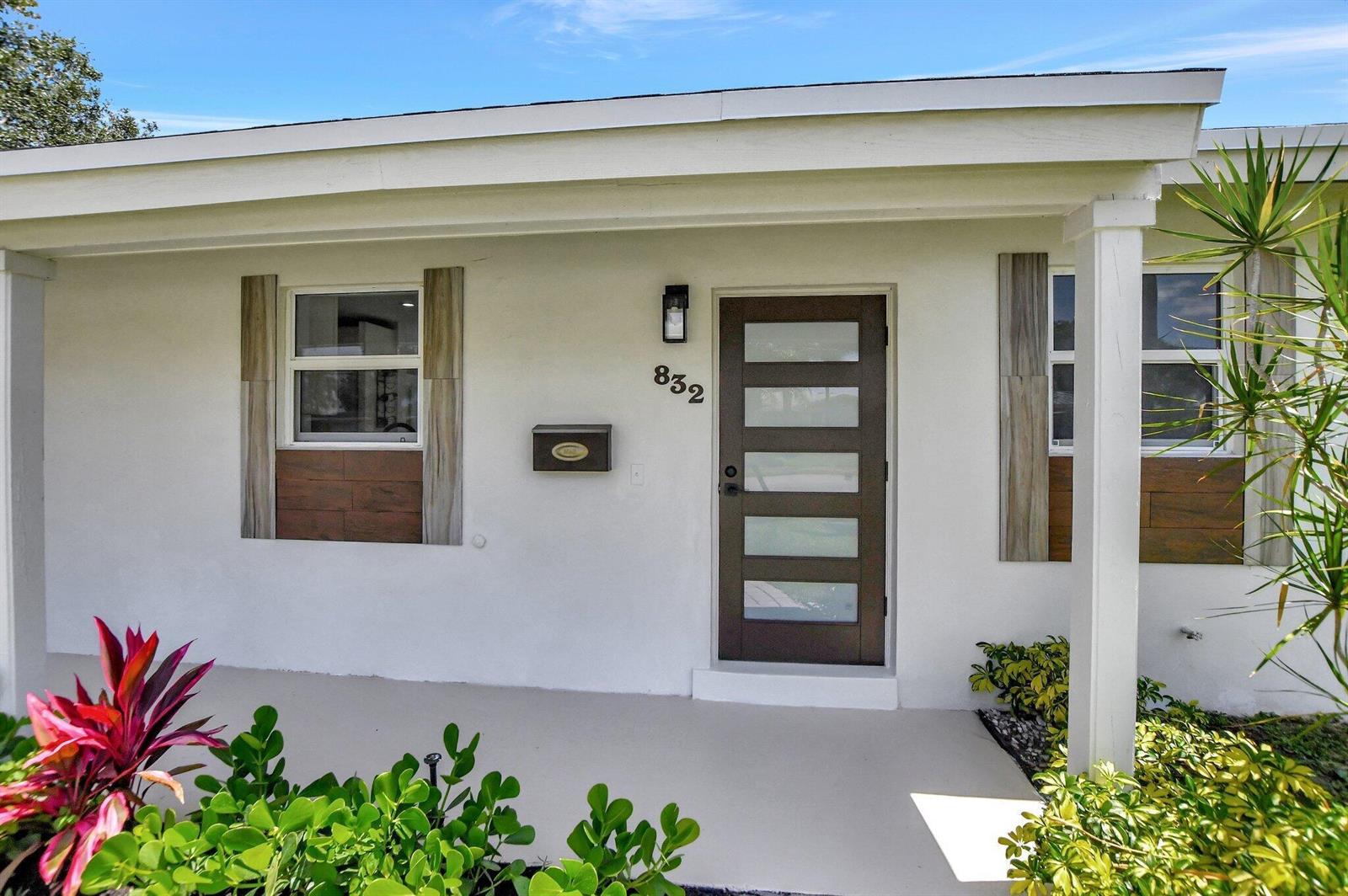 The exterior of a house features a white facade, a brown door, and wood-look shutters — 832 SW 10th Avenue, Boca Raton FL 33486, BOCA RATON, FL