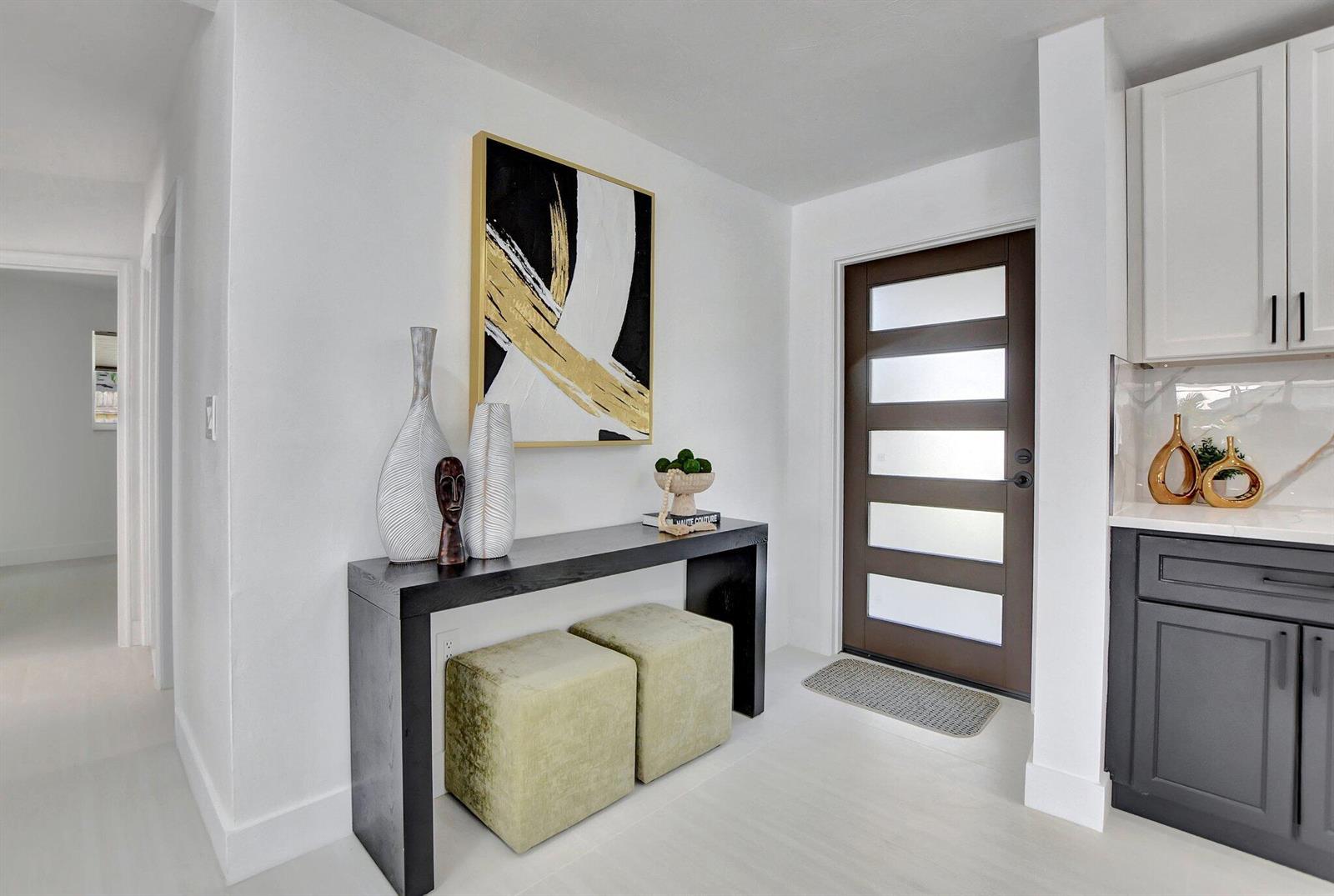 A modern entryway features a black console table, two green ottomans, and a dark front door — 832 SW 10th Avenue, Boca Raton FL 33486, BOCA RATON, FL