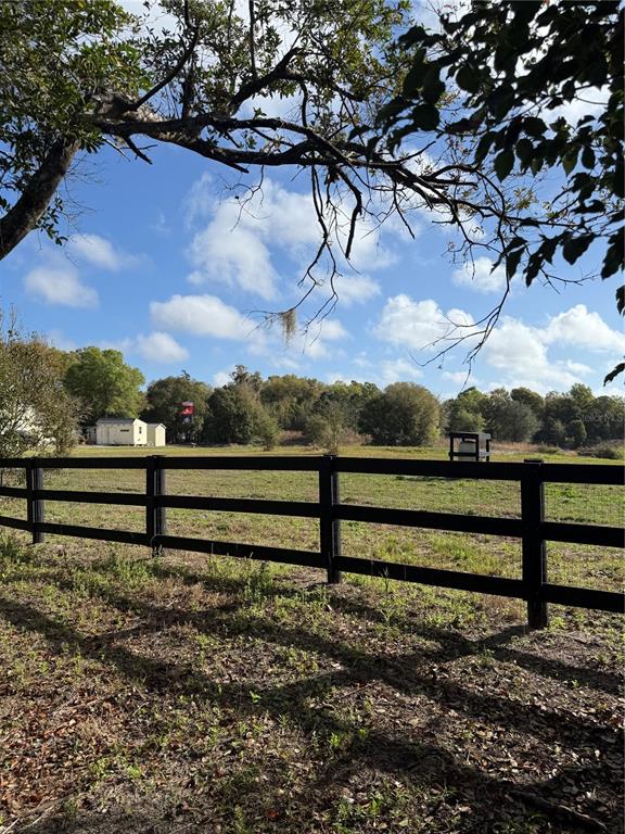 A black wooden fence borders a grassy field under a blue sky with trees — 1043 HAZEN ROAD, DELAND, FL