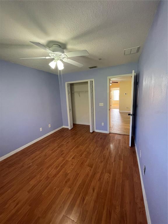 A bedroom with light purple walls, wood-look flooring, a ceiling fan, and an open closet — 227 GLOWING PEACE LANE UNIT 83, ORLANDO, FL