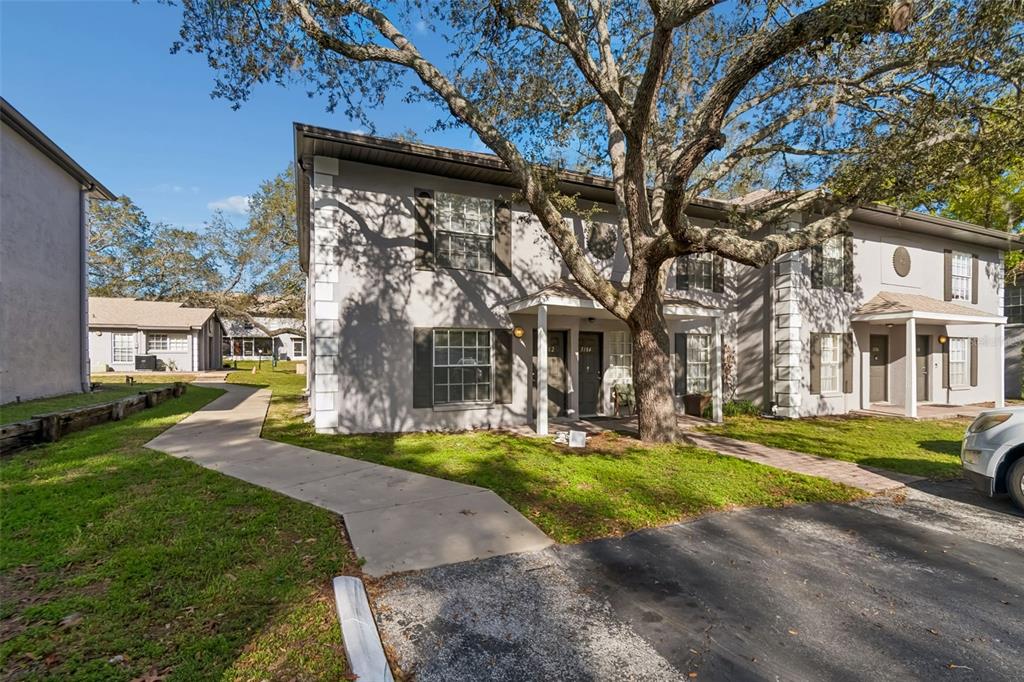 A two-story apartment building with gray stucco walls and a large tree in front — 5182 SUNRIDGE PALMS DRIVE UNIT 5182, TAMPA, FL