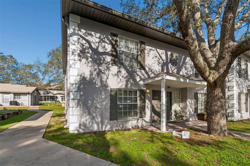 A two-story gray apartment building features white corner accents, dark shutters, and a covered entryway — 5182 SUNRIDGE PALMS DRIVE UNIT 5182, TAMPA, FL
