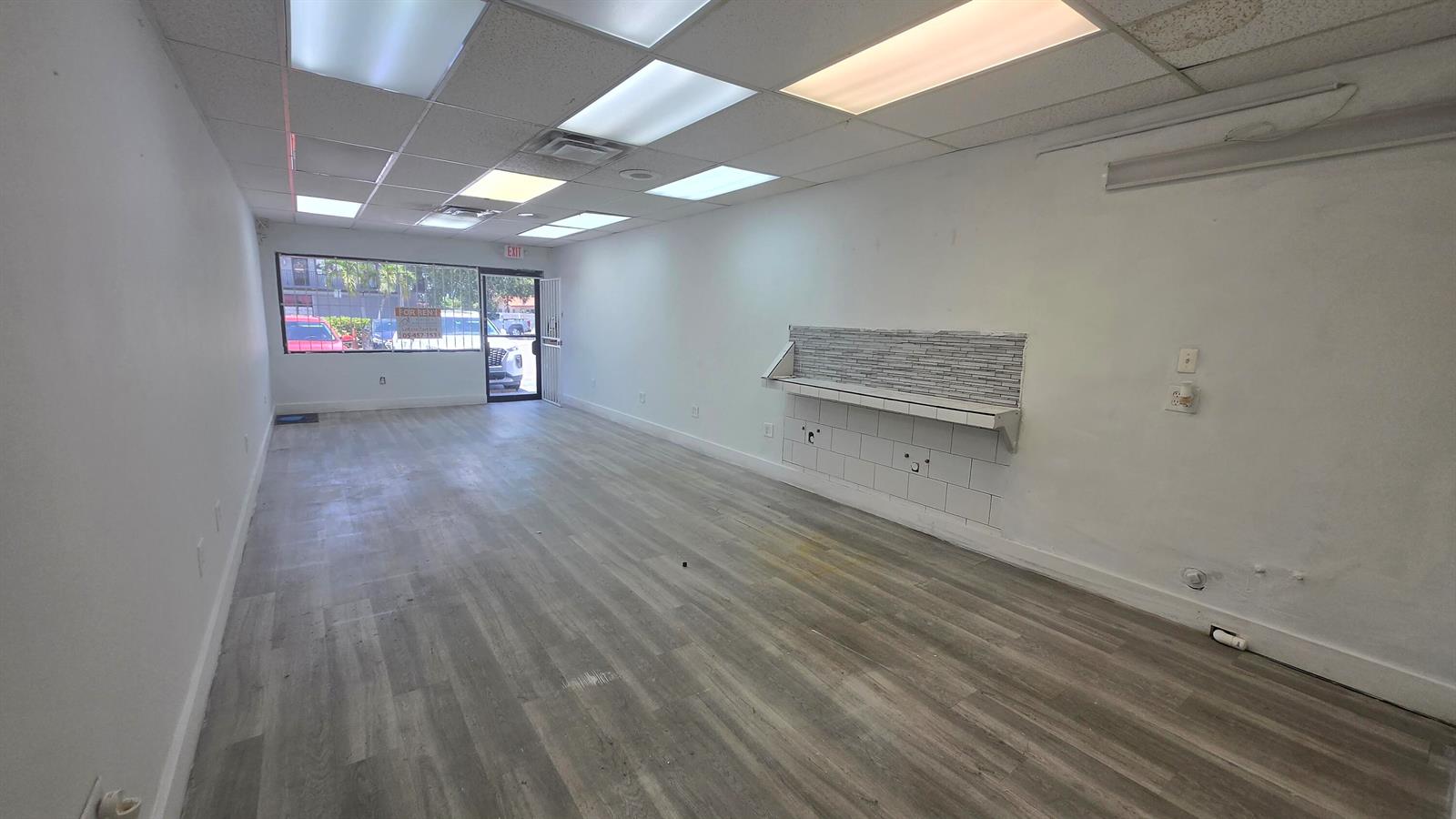 An empty commercial space features wood-look flooring, white walls, and a tiled service counter — 3300 E 4th Avenue # 5, Hialeah FL 33013, HIALEAH, FL