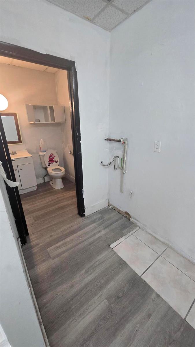 A bathroom with a toilet and vanity is visible through a doorway next to plumbing pipes — 3300 E 4th Avenue # 5, Hialeah FL 33013, HIALEAH, FL