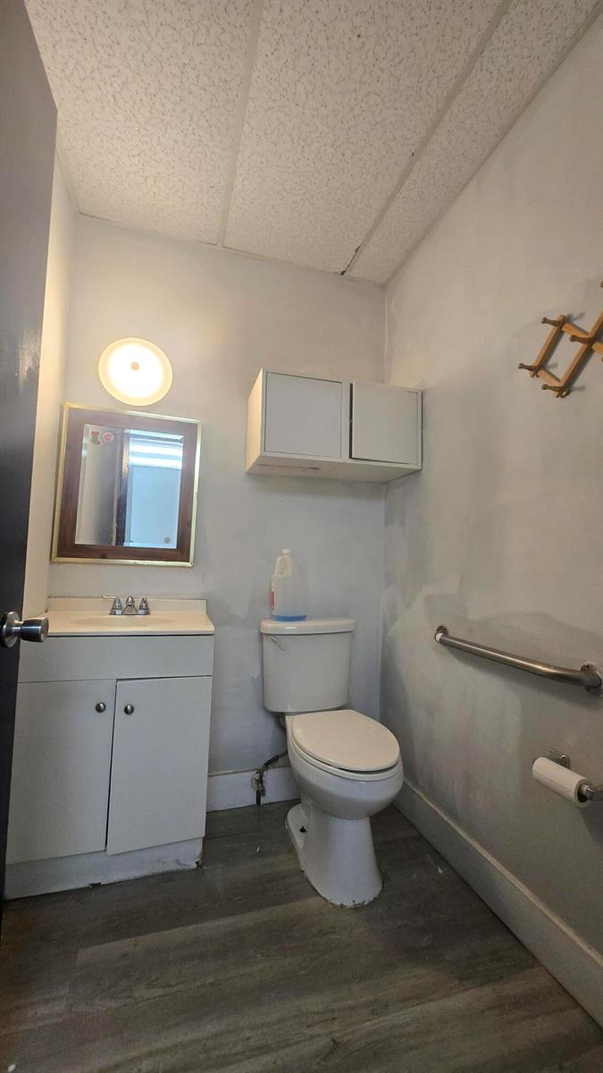 A small bathroom features a white vanity, a toilet, a wall-mounted cabinet, and grab bars — 3300 E 4th Avenue # 5, Hialeah FL 33013, HIALEAH, FL