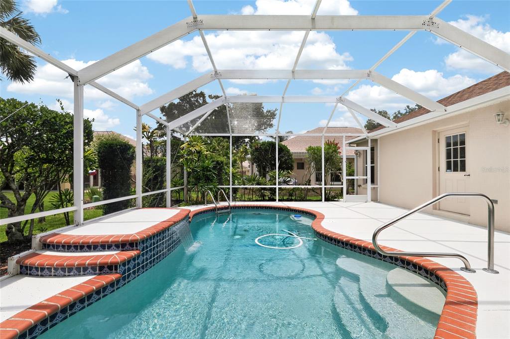 A screened-in swimming pool with a waterfall feature and red brick coping — 7240 SE 172ND LEGACY LANE, THE VILLAGES, FL